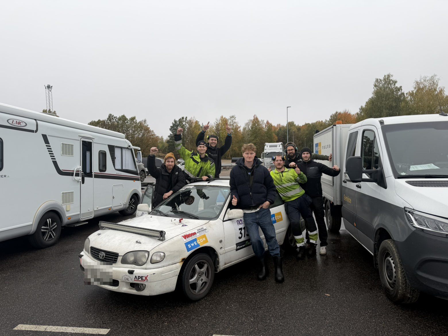 The NOF Racing team cheering around the white Corolla in the paddock